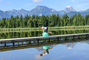 Pilates-Übungen auf einem Steg am Wasser