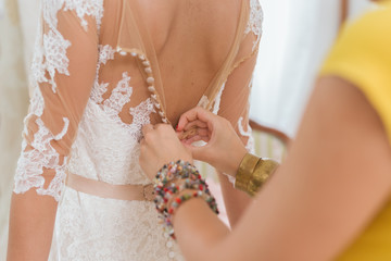 Obraz na płótnie Canvas A young bride being helped into her wedding dress