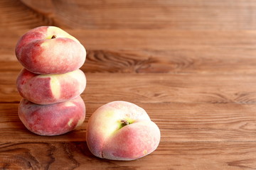 Sweet ripe flat peaches on the old wooden background. Fresh delicious fruits. Closeup 