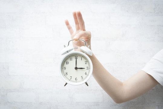 目覚まし時計を持った女性