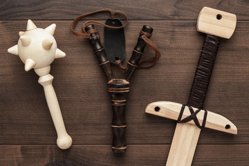 handmade wooden training toy sword, mace and slingshot on the table