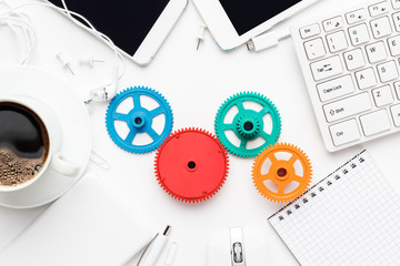 workflow and teamwork concepts with colorful gears different gadgets and office stationery on the...