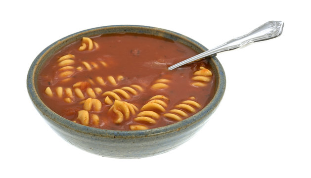 Rotini tomato soup in a bowl on a white background side view.