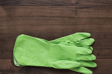 green rubber cleaning gloves on wooden background