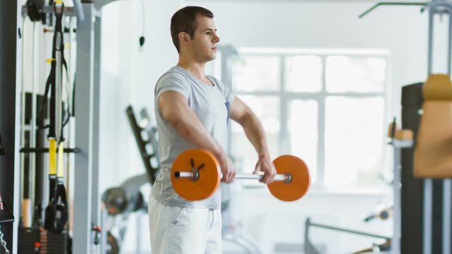 man makes exercises for the arms in gym. sports and healthy concept