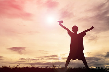 Fototapeta na wymiar Silhouette boy holding paper rocket on sunset