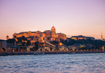 illuminated Budapest Castle at sunset with colorful sky on the background, beautiful view from Danube