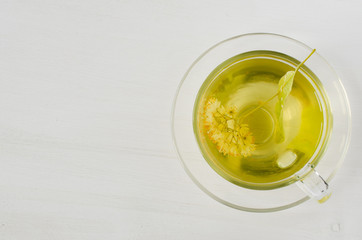 Cup of herbal tea with linden blossom on a white wooden background.