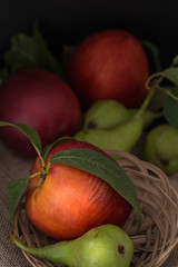 Organic pears and peaches on cloth closeup background, dark photography.