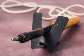 Old rusty soldering iron on the stand. Macro. Shallow depth of field. Focus on the tip of the soldering iron.
