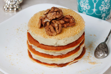 Pancake cake with cream and walnuts on a plate Still