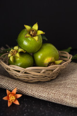 Green pomegranate in basket closeup background, dark photography.