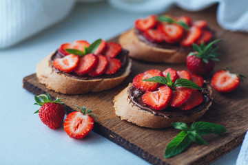 Strawberry bruschetta with chocolate paste and mint.Healthy thre
