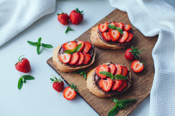 Strawberry bruschetta with chocolate paste and mint.Healthy thre