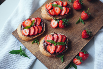 Strawberry bruschetta with chocolate paste and mint.Healthy thre