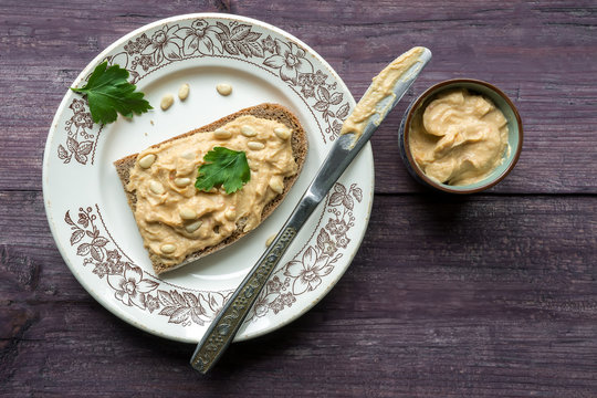 Hummus toast on wooden background. Traditional eastern food with chickpeas,  tahini and olive oil. Toast on wooden background. Top view