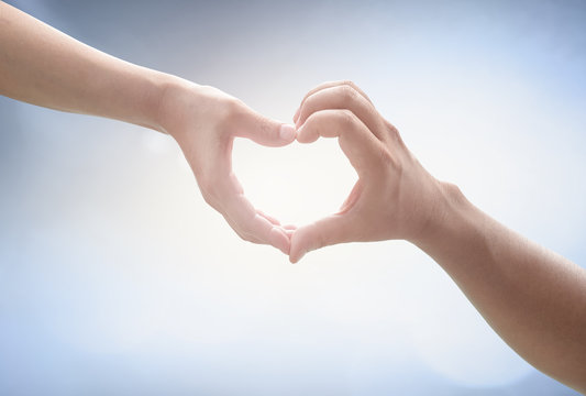 International women day concept: Two Human hands show heart shape on blurred blue nature background