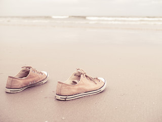 Yellow vintage canvas shoes on the sand beach