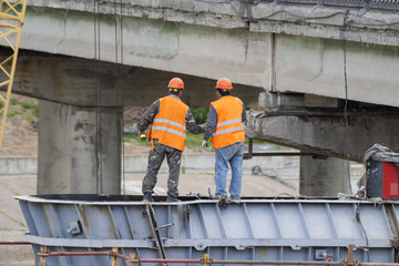 Workers assemble the bridge structure,Engineers discussing work plan.
