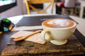 Latte art coffee cup on wooden plate