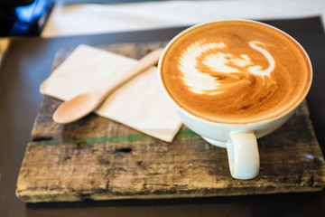 Latte art coffee cup on wooden plate