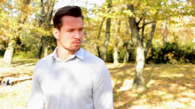 A young man walks in the woods, is a serious and looks around.
