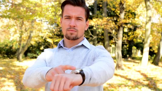 Young man stands in the woods and with a serious face shows on watch.