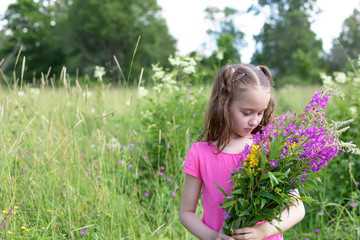 adorable girl with wildflowers. Child wearing pink dress playing in a summer field. Toddler kid with flower bouquet for birthday or mother's day.