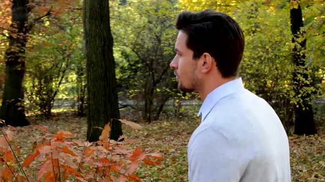 Overall detailed view of a young handsome man who is walks through the woods