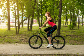 Fototapeta na wymiar Happy girl cyclist riding on a mountain bike outside