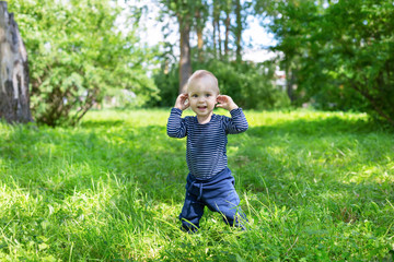 pretty baby boy standing in high grass in sun light