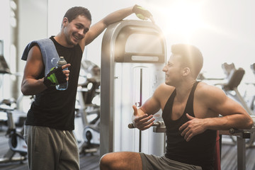 smiling men exercising on gym machine
