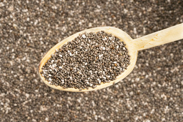 Healthy chia seeds on a wooden spoon over chia seeds background
