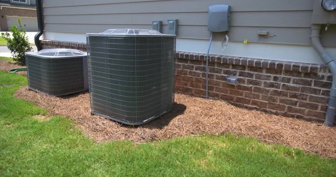 Two Central Air Conditioning Units Angled Rise Up. camera rises on a set of central air conditioning units on the side of a home. The electric meter is on the right side of the shot.
