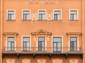 Several windows in a row and balcony on facade of urban apartment building front view, St. Petersburg, Russia.