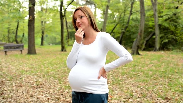 Young pretty pregnant woman think about something in park