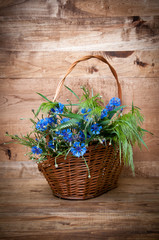 Fototapeta na wymiar Cornflowers in basket on wooden background