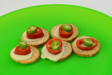Appetizers of melba toast, melted mozzarella cheese, jalapeno peppers and hot peppers
