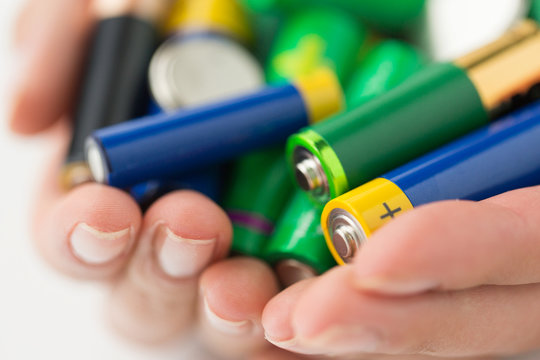 close up of hands holding alkaline batteries heap