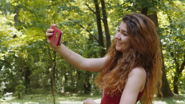 Happy young woman taking selfie with the smartphone in the park