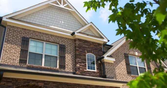 Brick Home Exterior Top Close Up. camera slowly lowers with a tree in the foreground of a modern brick and stone home exterior close up of the top half of the home
