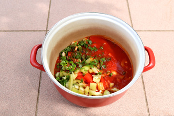 Sliced tomatoes, green peppers, parsley and scallions with tomato sauce, in a pot. 