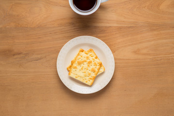 Bread crackers in white plate, cup of coffee