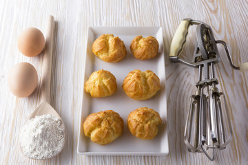 Tasty eclairs, eggs, flour and handle mixer.
