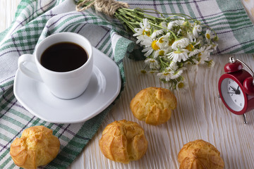 Eclair, coffee cup, alarm clock and charmomile.