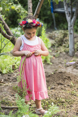 Little girl wearing flower wreath harvesting carrots from backyard garden © alexandrum01