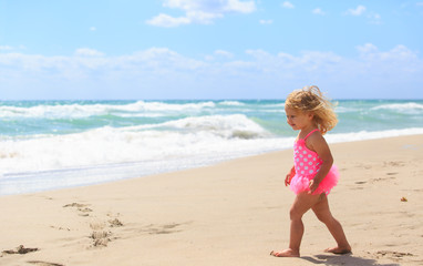 Fototapeta na wymiar little girl walk on sand beach