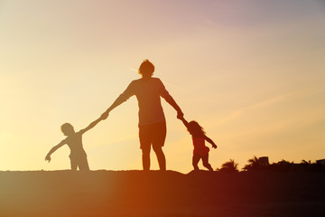 Fototapeta premium father with son and daughter silhouettes play at sunset