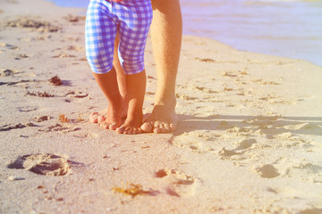 Close up of father and little daughter feet on beach