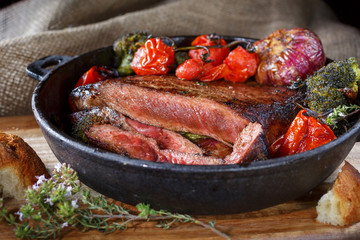 Beef steak medium rare with vegetables on a cast iron skillet. still life of food in low key. a dish of European cuisine. food in rustic style
